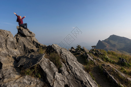 女游客坐在岩石的最顶端在日落时景色优美的DoiPhaTang旅游点Sunset景点清Rairsqopos隐藏天堂泰国DoiTan图片