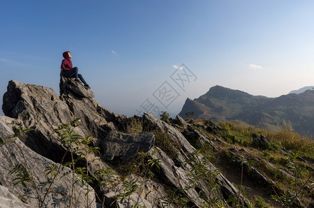 徒步旅行美丽的爬坡道女游客坐在岩石的最顶端在日落时景色优美的DoiPhaTang旅游点Sunset景点清Rairsqopos隐藏图片