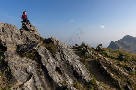 女游客坐在岩石的最顶端在日落时景色优美的DoiPhaTang旅游点Sunset景点清Rairsqopos隐藏天堂泰国DoiTan图片