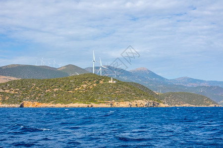 岛地中海科林斯湾的希腊山丘海岸阳光明媚的旧灯塔大楼以及许多风力农场山岸和灯塔水图片