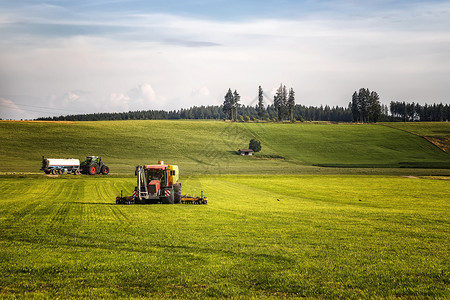 与在德国田地工作的重型拖拉机一起在可耕地上施用粪肥天有机的图片