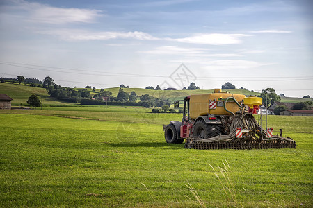 与在德国田地工作的重型拖拉机一起在可耕地上施用粪肥机械夏天运输图片