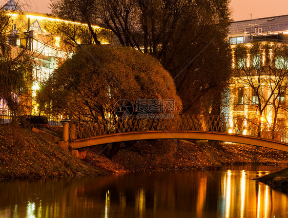 场景横跨河流的桥在灯光房屋的背景下夜幕发生观反射图片