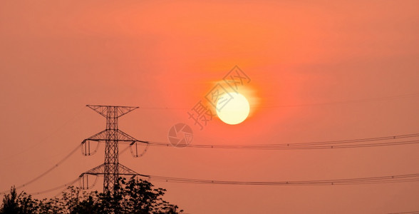 日落时高压电线杆和输黄昏时有橙色和红天空云彩在日落时有太阳光电和能源节的太阳和行业植物分配图片