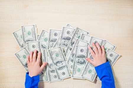 货币成人顶视图手数钱的特写快乐孩子用美元小商人一堆美元百钞票在男孩手中美元纸币金融图片