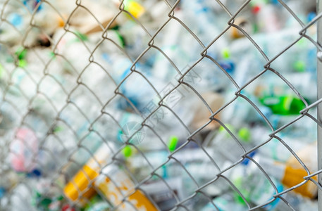网状围栏中空水塑料瓶装罐堆积的模糊照片回收使用塑料瓶废物于回收企业塑料废弃物管理减少和再利用塑料PET垃圾以及减少和再利用塑料生图片