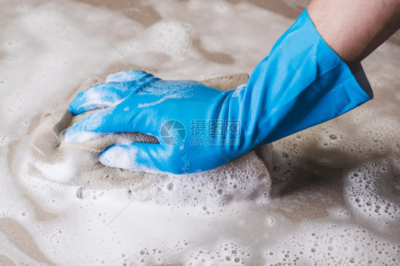 具体的戴蓝橡胶手套人正在用海绵清洗瓷砖地板工业的国内图片