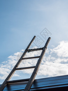 梯子竹靠在金属屋顶上明蓝的天空下维持保养时间蓝色的楼梯图片