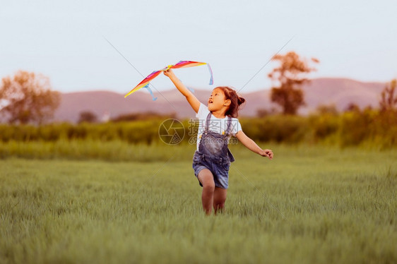 乐趣亚洲女孩和父亲带着风筝跑来去夏天在草地上快乐的亚洲女孩和父亲飞年轻的图片
