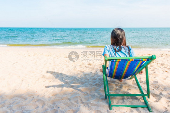 漂亮女孩背坐在沙滩上图片