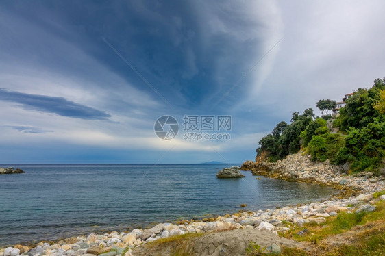 日出希腊夏季海景空岸和一座小别墅在绿树中夜边海湾和戏剧天空的叶子图片