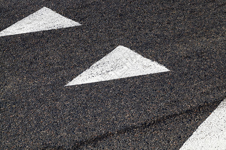 白色道路标记用黑色沥青涂上白箭标明汽车行驶方向白色近路标记以白色箭形式绘制的白色道路标记巷慢的指示图片