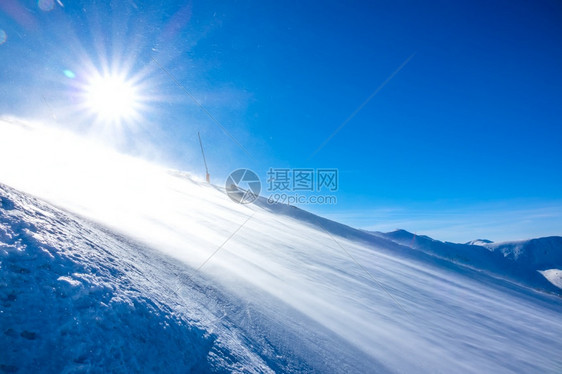 自然霜强烈的风吹起许多雪尘在太阳中闪耀着光下的雪暴在天晴时空滑雪斜坡上地形图片