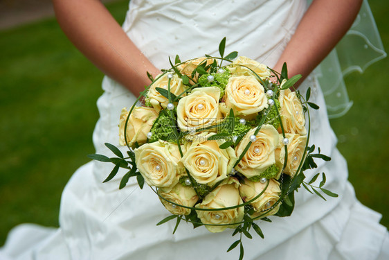 举行婚礼的新娘手中的白玫瑰花束图片
