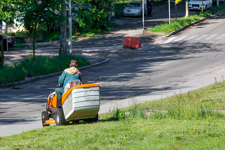 户外公用工人负责修路边草坪用专业的割草机剪高以复制空间为图象A公用工人通过砍高草来照顾路边地春天公园图片