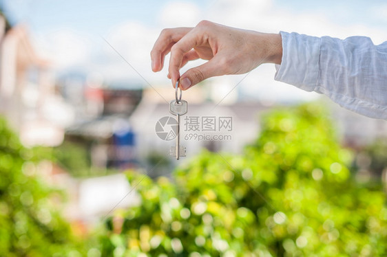 住宅一名持房子钥匙的男在城市房屋背景上持有家用钥匙处理房地产概念问题负责不动产概念的人持房子钥匙负责城市房屋背景情况处理不动产概图片