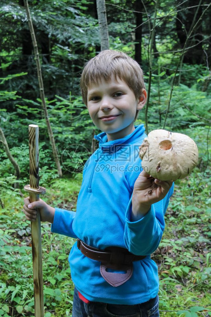 景观在森林里微笑的男孩手里拿着大蘑菇玩具林地图片