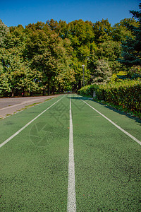 在人造地盘的空绿色运动场上在阳光明媚绿草和阳光的体育田里在阳光明亮的媚日天球场上一种跑步机锻炼图片