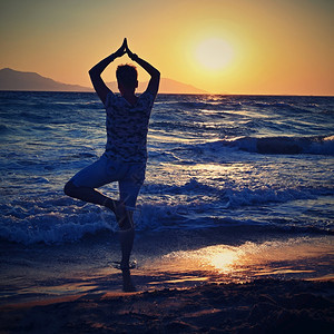 经过宁静红色的妇女冥想日落时在海滩的边放松瑜伽健康和SPA的概念图片