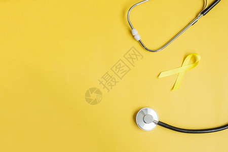 幸存者诊断9月预防日儿童癌症意识月和世界癌症日概念关于黄色背景的丝带和Stethoscope以支持生活和患病者支持黄色背景9月慈图片