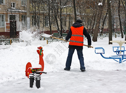 塑料单身的冬季在游乐场除雪一个人拿着铲子从铁轨上扫雪干净的图片
