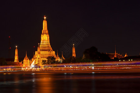 泰国宗教的黄昏华特阿龙灯光照亮了寺庙和河上的船只交通天空图片