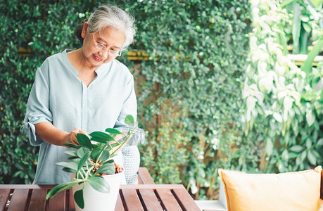 一位快乐和微笑的亚洲老年妇女在退休后家里安放业余爱好为老年人创造幸福生活方式和良好健康的概念对年长者来说外部春天为了图片