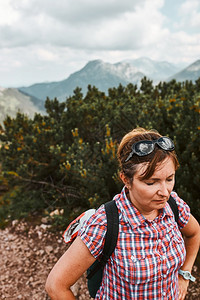 自然女游客背着包徒步登山的女人积极度过暑假上山后休息站在木戈松的山路上背包徒步旅行的女人图片