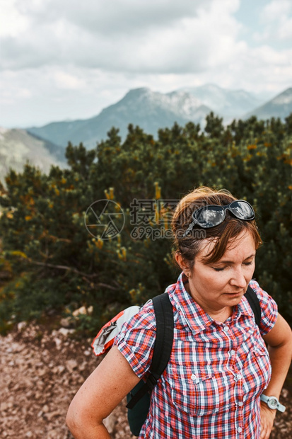 自然女游客背着包徒步登山的女人积极度过暑假上山后休息站在木戈松的山路上背包徒步旅行的女人图片