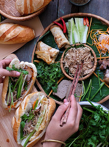 越南语蔬菜女人的手可以做banhmithit或越南面包有名的街头食物来自原料猪肉火腿梨子蛋和新鲜草药如扇菜椰胡萝卜黄瓜辣椒街头食图片