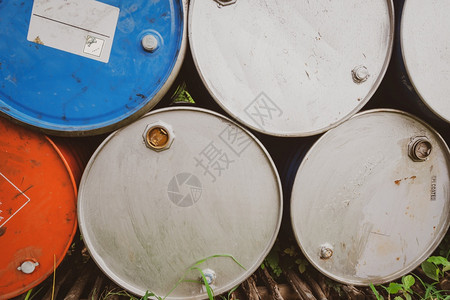 老的汽油堆叠旧化学品桶蓝色和橙油桶钢罐有毒废物仓库带有警告标签的危险化学品桶金属中的工业废物厂危险储存图片