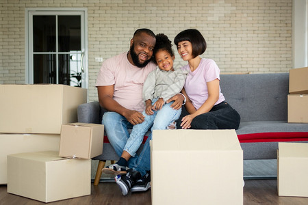 母亲父混合种族家庭在购买房地产后第一天搬到新房子后就坐在沙发上休息新的家庭开始生活的概念是新家庭开始生活的概念微笑图片