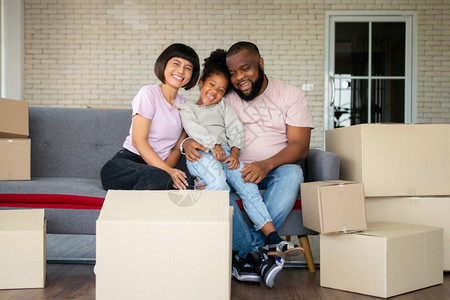 里面人们混合种族家庭在购买房地产后第一天搬到新房子后就坐在沙发上休息新的家庭开始生活的概念是新家庭开始生活的概念坐着图片