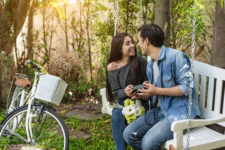 人们亚洲夫妇在自然公园与行车一起坐在桌椅上的浪漫时刻有眼神接触的亚裔夫妇和骑自行车的人以及情节和婚礼仪式的生活方概念初见主题爱吻图片
