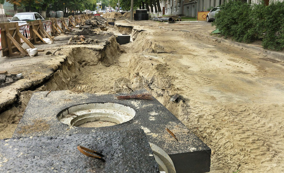 沥青流走城市收集器的水泥块井和管道位于街路上修复城市下水道的公路上挖掘沟附近b市政收集器的水泥砖井和管道户外图片