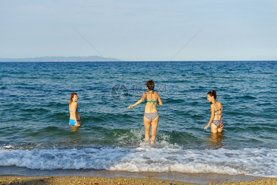 水夏天3名年轻女孩朋友在海边或的滩上穿着比基尼泳衣渡假日阳光明媚年轻的图片