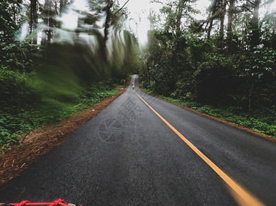 在雨季乘摩托车林的山上骑着摩托车在路上行驶时比克正骑着摩托车自行尽管速度图片