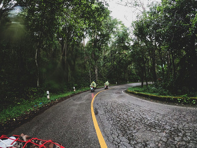 闲暇在雨季乘摩托车林的山上骑着摩托车在路上行驶时比克正骑着摩托车风景绿色图片