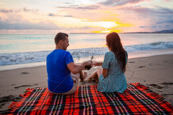 在热带海滩上快乐的美丽家庭一起野餐在夕阳日落一家在海滩上野餐幸福女士岛图片