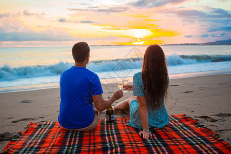 放松毯子在热带海滩上快乐的美丽家庭一起野餐在夕阳日落一家在海滩上野餐食物图片