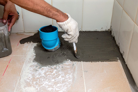 建筑工人正在洗手间瓷砖地板上刷防水泥在清扫安全手动的处理图片