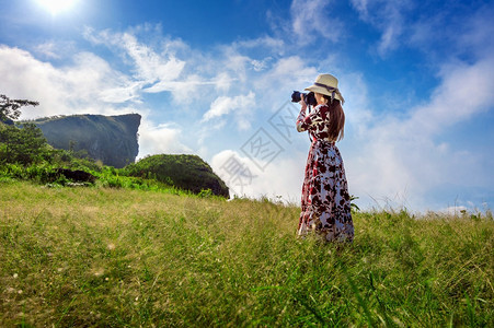 公园天空女站在草地上并持着相机在泰国清莱PhuChiFa山拍照闲暇图片