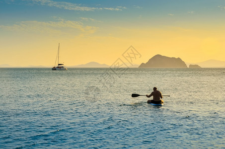 在海中划船的男子夜晚橙色天空年轻的旅行健康图片