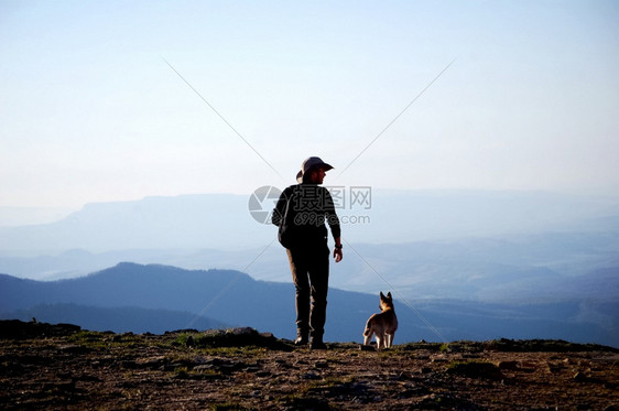 一个男人带着狗在山谷上方的悬崖男人带着狗在山谷上方的悬崖树棕色乡村图片