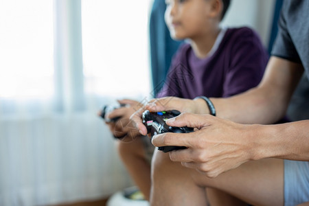 父母年轻的泰国亚洲父亲和儿子在家中客厅玩电子游戏时享受与高跟棍一起玩电游戏兴奋地非常有趣玩起居室游戏图片