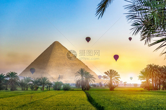 夏天在绿地的Egyptian金字塔上方的空气球位于雾中清晨幻想风景的绿地田里有Egyptian金字塔地平线景观图片