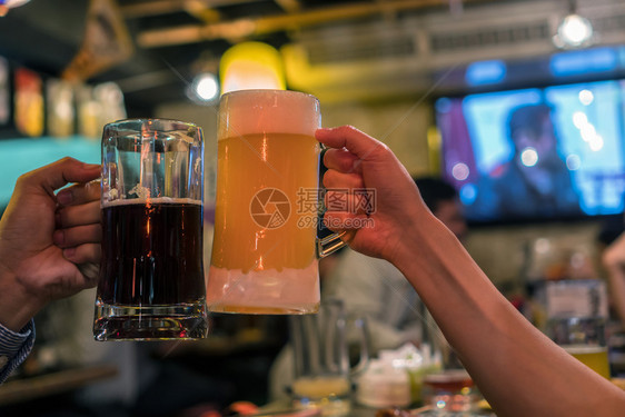 两杯啤酒在吧朋友之间一起欢呼餐厅休息和喝酒的概念笑声气泡曼谷手图片