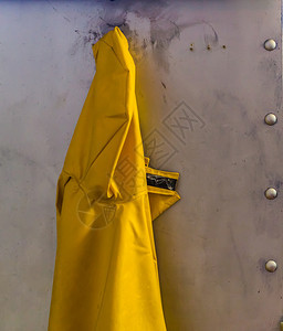 男女通用的黄色挂在金属墙上黄色雨衣海洋背景雨季防护服和天随意的图片