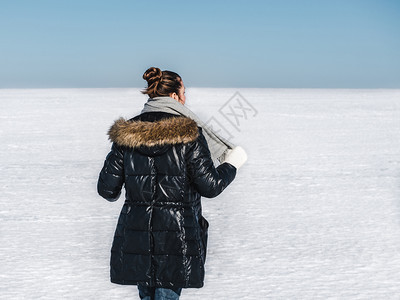 夹克黑发快乐年轻女在雪地的背景一个晴朗阳光明媚的一天幸福女在雪地背景新的图片
