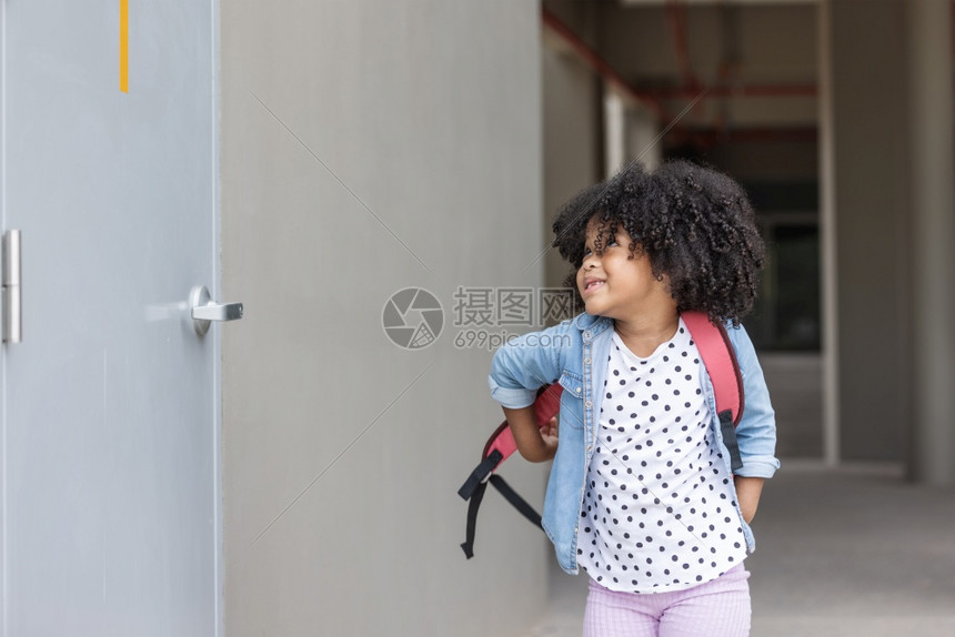 课一个小卷发女孩背包通过学校走廊的背景瞳孔微笑图片